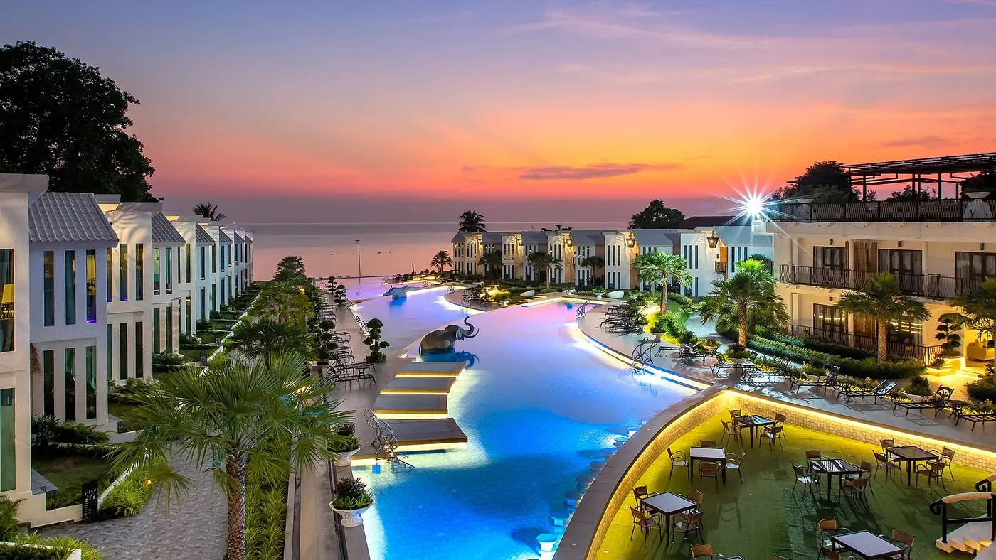 The pool and terrace at Vannee Golden Sands under a pink dusk sky